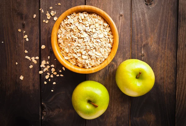 Oat flakes in bowl and two apples — Stock Photo, Image