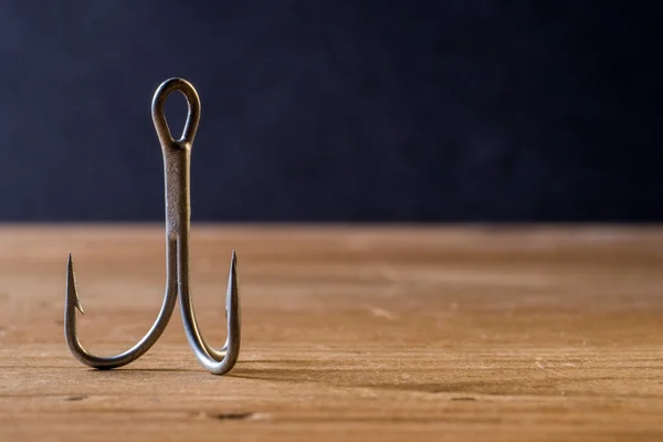 Fish Hook on a wooden surface with dark background Stock Picture