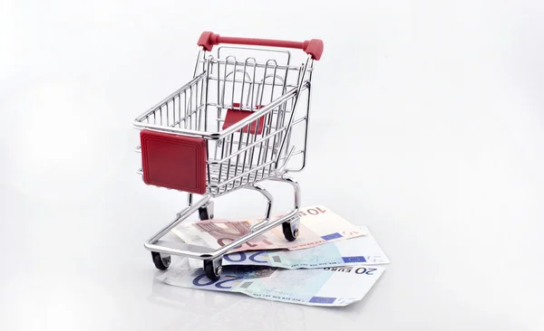 Conceptual studio shot of a bunch of euro banknotes filling a shopping cart on white background — Stock Photo, Image