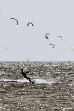 Genç bir Akdeniz erkeğinin silueti uçurtmaya gidiyor. Siyah bir dalış kıyafetiyle suda ve uçurtmayı uçurmak üzere. Siyah ve Beyaz çekimi.