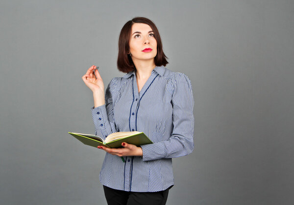 Thoughtful woman looking away while thinking. Write on her notes