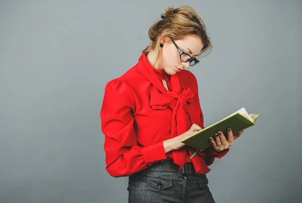 Mulher pensativa em blusa vermelha olhando em suas notas — Fotografia de Stock