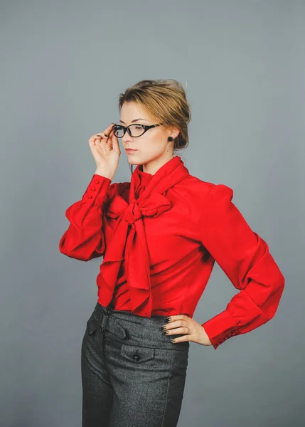 Thoughtful woman in red blouse and glasses looking away