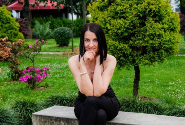 Güzel, esmer bir kadın parkta dinleniyor, taşın üzerinde oturuyor. Gülümse, Batumi, Georgia 'daki tatlı kız. Yaz zamanı..