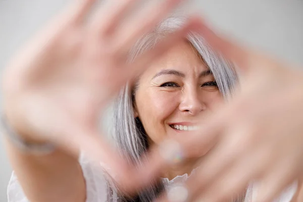 一个灰色背景的苍白的长发亚洲成熟女人的情感画像 — 图库照片