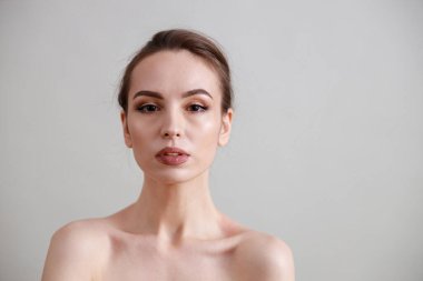 Stüdyo güzelliği portresi. Gri bir arka planda genç, sağlıklı, güzel, taze tenli beyaz bir kadın.