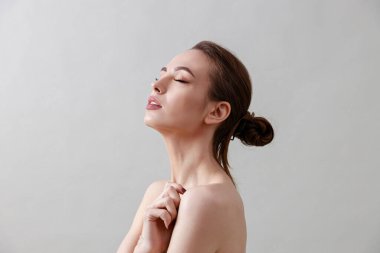 Stüdyo güzelliği portresi. Gri bir arka planda genç, sağlıklı, güzel, taze tenli beyaz bir kadın.