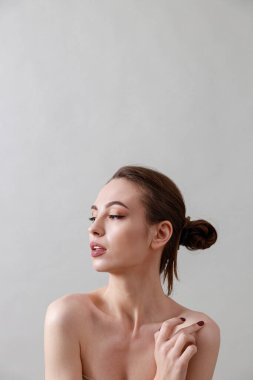 Stüdyo güzelliği portresi. Gri bir arka planda genç, sağlıklı, güzel, taze tenli beyaz bir kadın.