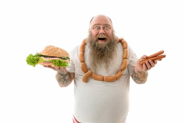 Duygusal açıdan şişman, komik ve dövmeli bir adam. Beyaz bir arka planda izole edilmiş yiyecekleri var.