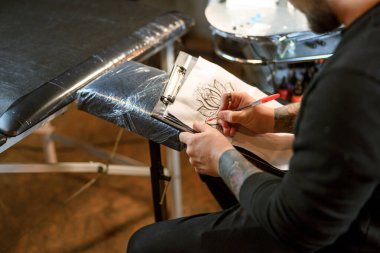 Profesyonel Sakallı Kafkas dövme ustası rahat atmosferik stüdyoda çalışıyor.