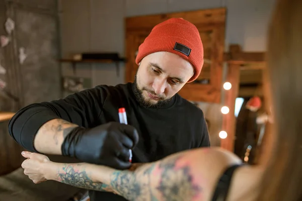 プロの男性ひげそり白人タトゥーマスターは居心地の良い雰囲気のスタジオで働いています — ストック写真