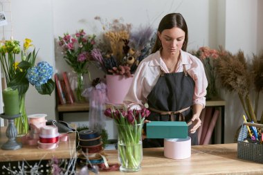 Profesyonel çiçekçi genç bayan çiçekçide buket yapıyor.
