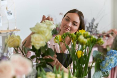 Profesyonel çiçekçi genç bayan çiçekçide buket yapıyor.