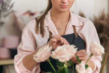 Profesyonel çiçekçi genç bayan çiçekçide buket yapıyor.