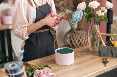 Profesyonel çiçekçi genç bayan çiçekçide buket yapıyor.