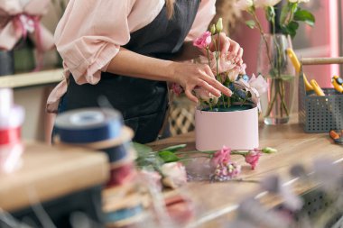 Profesyonel çiçekçi genç bayan çiçekçide buket yapıyor.
