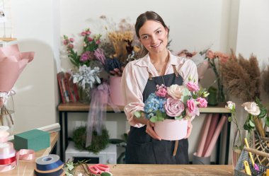 Profesyonel çiçekçi genç bayan çiçekçide buket yapıyor.