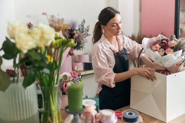 Profesyonel çiçekçi genç bayan çiçekçide buket yapıyor.