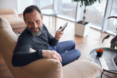 Mutlu yetişkin erkek işadamı rahat bir ofiste oturuyor ve dinleniyor.