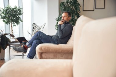 Mutlu yetişkin Kafkasyalı adam dinlenme odasında oturuyor ve dinleniyor.