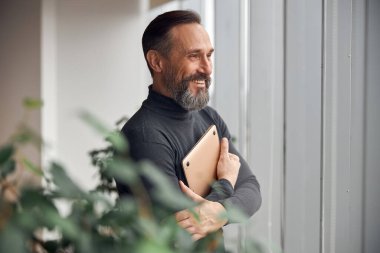 Mutlu yetişkin beyaz adam modern bir ofiste çalışıyor.