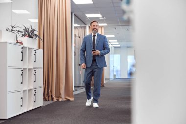 Mutlu yetişkin beyaz adam modern bir ofiste çalışıyor.