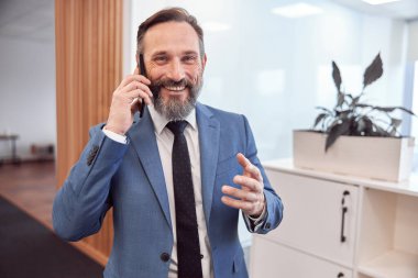 Kafkasyalı mutlu iş adamı modern şık bir ofiste akıllı adam kullanıyor.