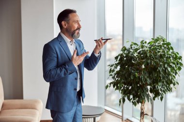 Mutlu yetişkin beyaz adam modern bir ofiste çalışıyor.