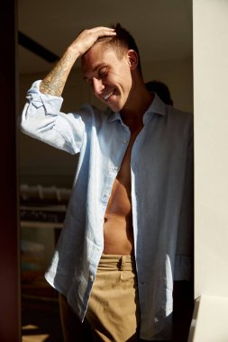 Mutlu, güzel, yakışıklı, gülümseyen beyaz adam sabah güneşinde modern ışık evinde dinleniyor.