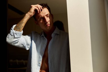 Mutlu, güzel, yakışıklı, gülümseyen beyaz adam sabah güneşinde modern ışık evinde dinleniyor.