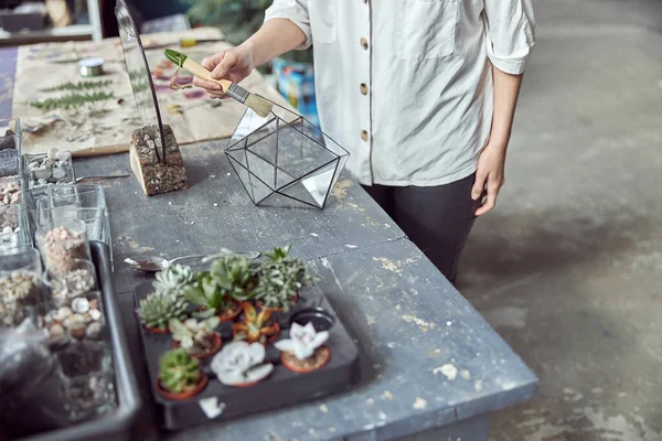 Caucasian confident happy florist is working with composition made from glass stones and plants in botanic shop — Stock Photo, Image