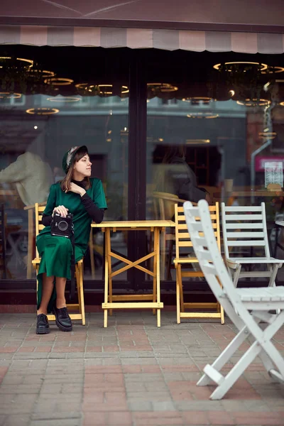 도시에서 녹색 옷을 입은 행복 한 여성 이 카페 근처에 앉아 있습니다. — 스톡 사진