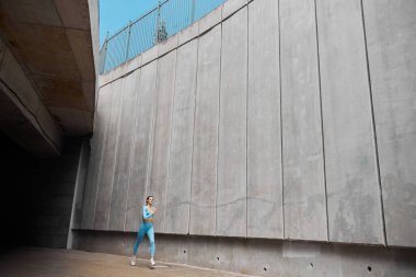 Güzel formda genç bir bayan koşucu dışarıda koşuyor.