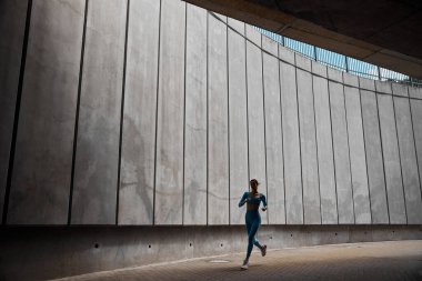 Güzel formda genç bir bayan koşucu dışarıda koşuyor.