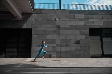 Güzel formda genç bir bayan koşucu dışarıda koşuyor.