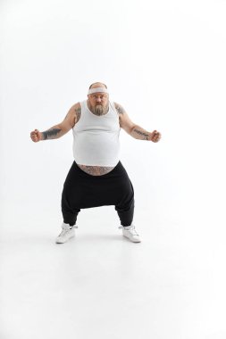 Büyük göbekli ve spor dövmeli mutlu şişman adam beyaz arka planda poz veriyor.