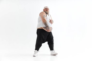 Koca göbekli, spor elbiseli ve dövmeli mutlu şişman adam karnını tutuyor.