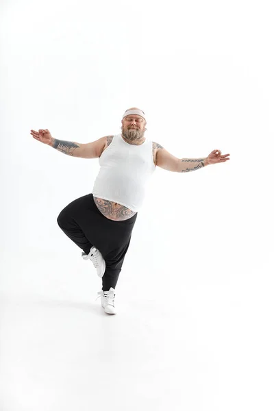 Happy dikke man met grote buik en tattoes in sportkleding poseren op witte achtergrond — Stockfoto