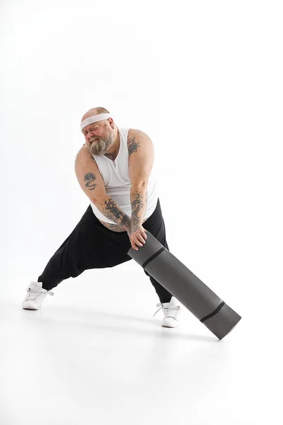 Χαρούμενος χοντρός με μεγάλη κοιλιά και τατουάζ στα αθλητικά ενδύματα με χαλάκι γυμναστικής — Φωτογραφία Αρχείου