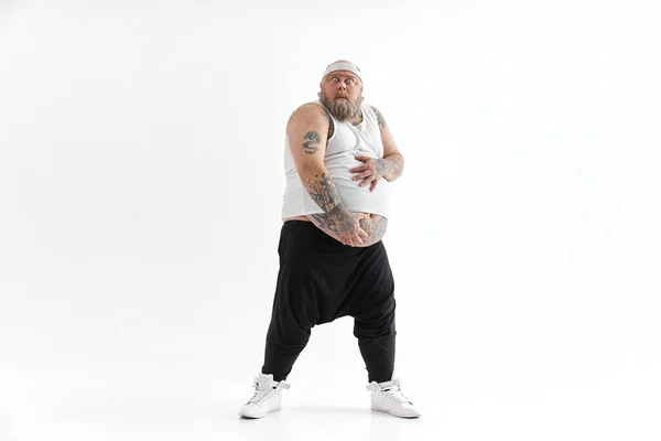 Gelukkige dikke man met grote buik en tattoes in sportkleding houdt zijn maag vast — Stockfoto