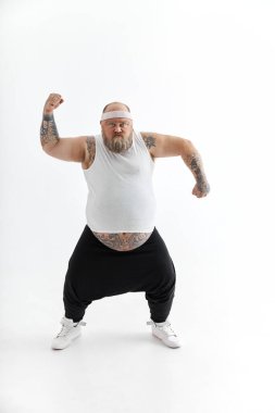 Büyük göbekli ve spor dövmeli mutlu şişman adam beyaz arka planda poz veriyor.