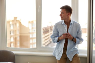 Mutlu, güzel, yakışıklı, gülümseyen beyaz adam modern ışık evinde dinleniyor.