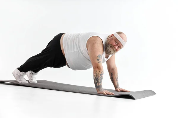 Sportieve dikke man met baard en tatoeages doet aan yoga — Stockfoto