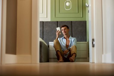 Zeytin duvarının yanında genç ve mutlu bir adam vakit geçiriyor ve gülümsüyor