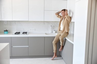 Mutlu yakışıklı adam minimalist mutfakta duruyor ve gülümsüyor.