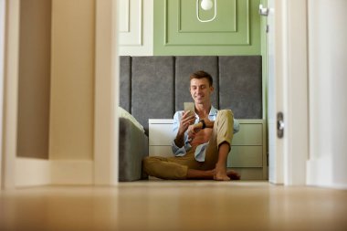 Zeytin duvarının yanında genç ve mutlu bir adam vakit geçiriyor ve gülümsüyor