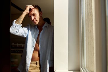 Mutlu, güzel, yakışıklı, gülümseyen beyaz adam sabah güneşinde modern ışık evinde dinleniyor.