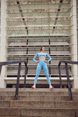 Genç, formda bayan spor yapıyor ve şehir merkezinde koşuyor.