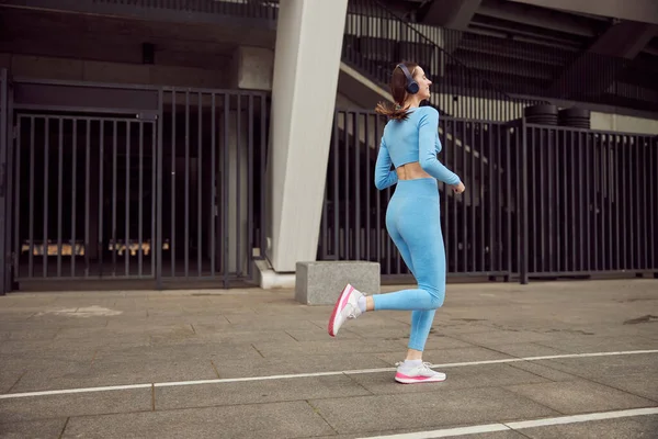Slim joven caucásica dama está haciendo deportes al aire libre en el lugar urbano —  Fotos de Stock