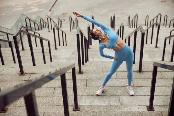 Joven dama en forma está haciendo fitness y jogging en el lugar urbano — Foto de Stock